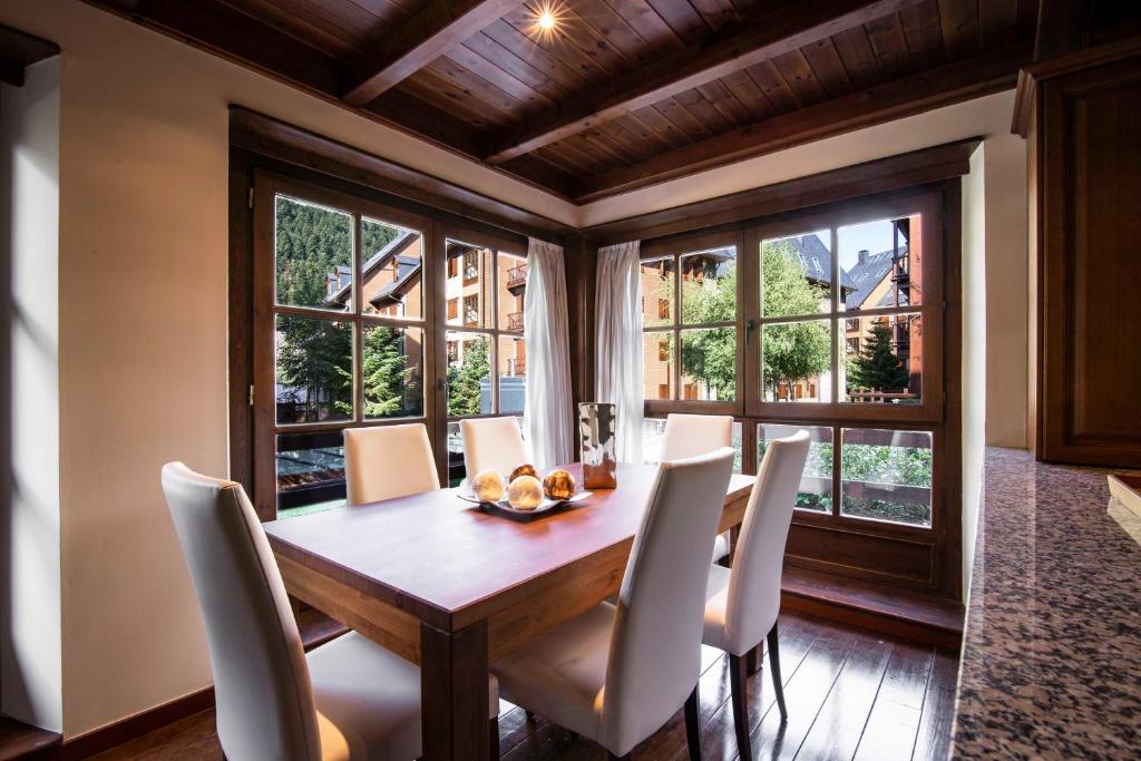 a dining room with a table and chairs and windows at MONTOLIU de Alma de Nieve in Baqueira-Beret