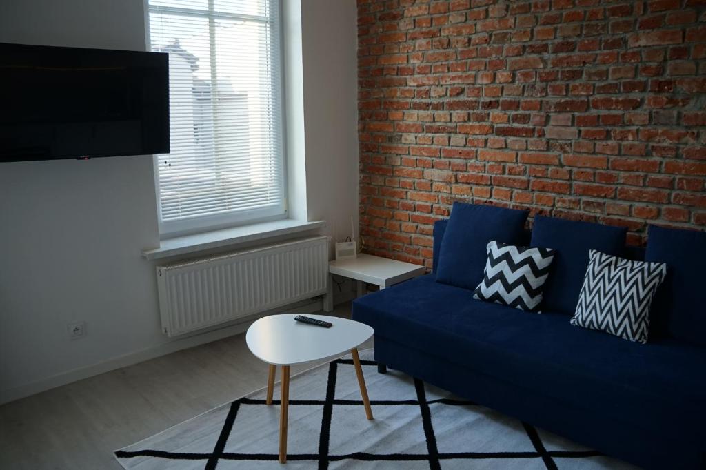 salon z niebieską kanapą i ceglaną ścianą w obiekcie Apartament Gliwice Centrum Witkiewicza I w mieście Gliwice