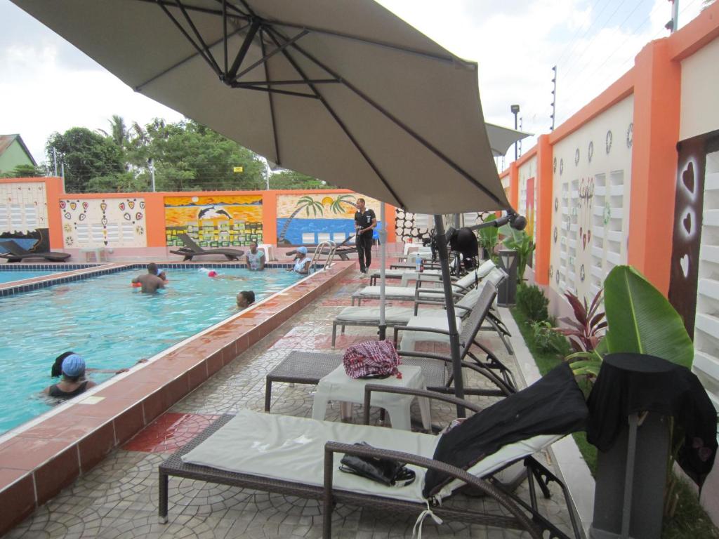 una piscina con una fila de sillas y una sombrilla en Jakicha Motel, en Dar es Salaam