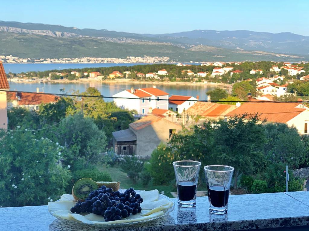 a plate of fruit sitting on a table with two glasses at Apartment Rozi in Šilo
