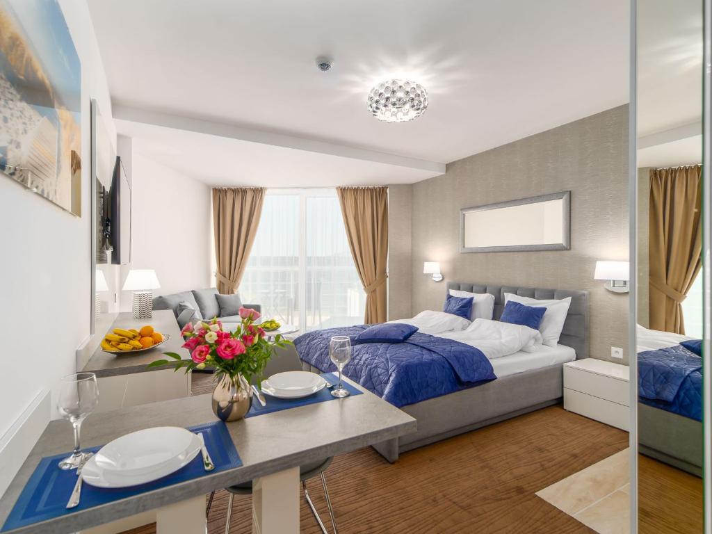 a bedroom with a bed and a table with plates on it at Seaside Park Apartament Prywatny Kołobrzeg Lokservis - przy plaży in Kołobrzeg