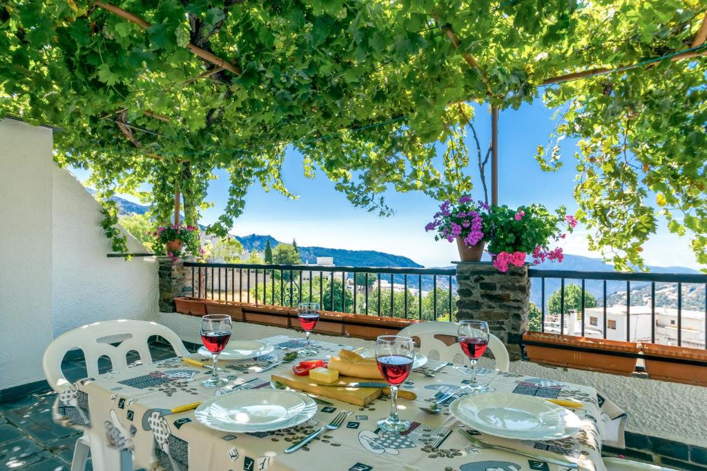 einen Tisch mit Gläsern Wein auf dem Balkon in der Unterkunft Alojamiento Los Pradillos in Capileira