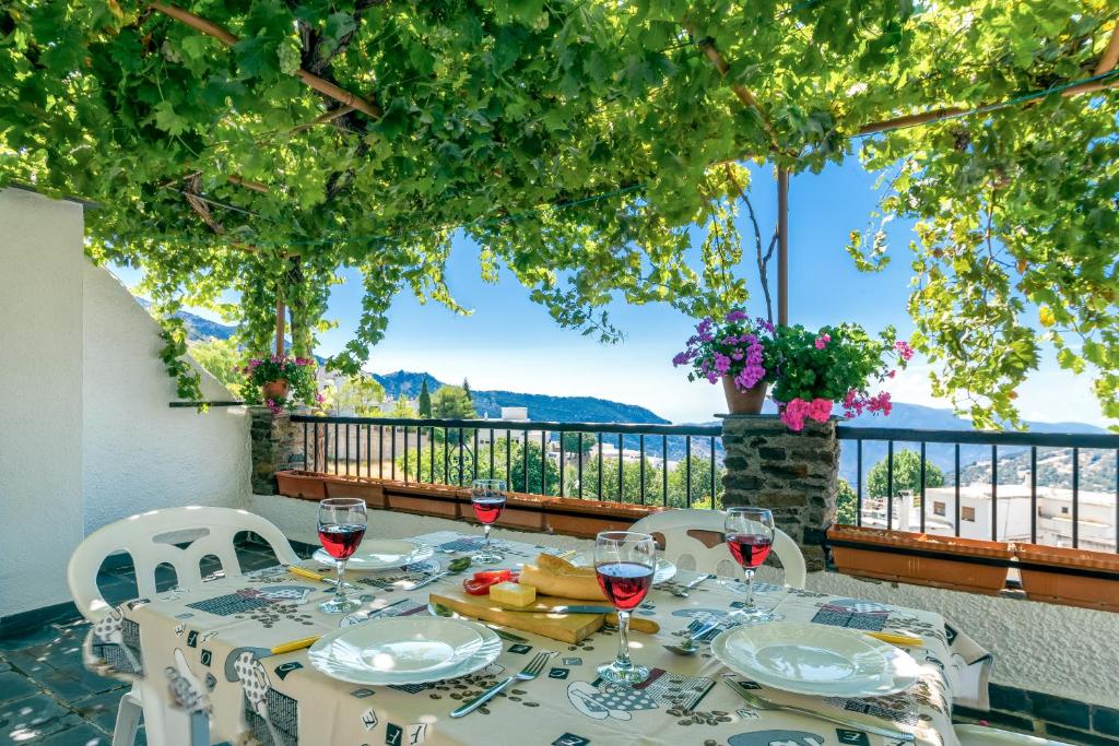 una mesa con copas de vino en el balcón en Alojamiento Los Pradillos en Capileira