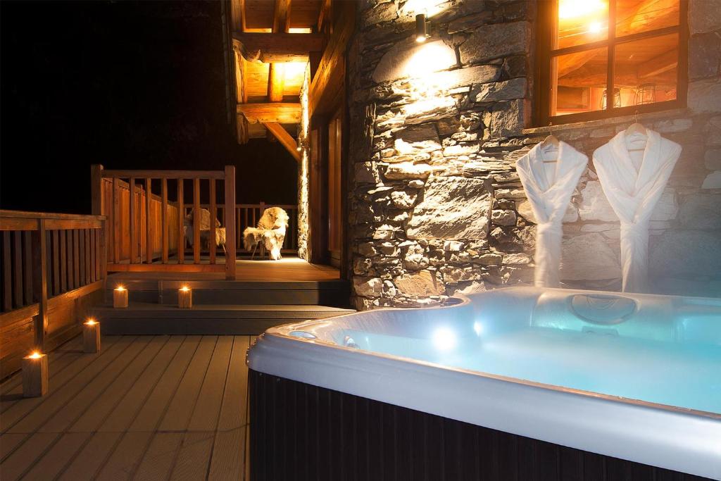 a bath tub in a stone building with a dog in the background at Madame Vacances Le Chalet Arosa in Le Joseray