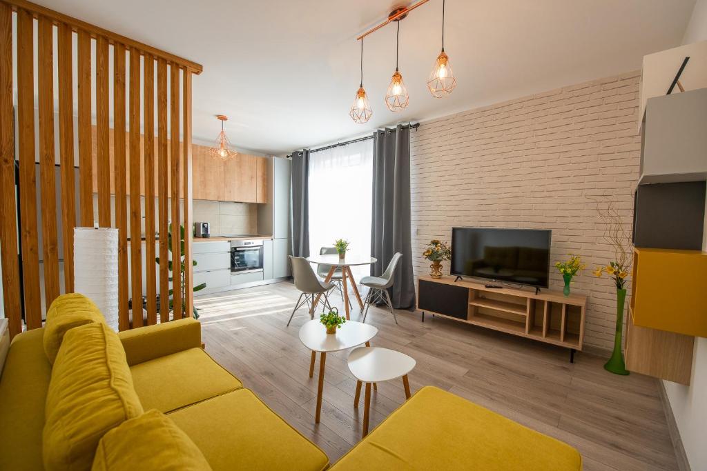 a living room with a yellow couch and a television at ART Apartment in Târgu-Mureş