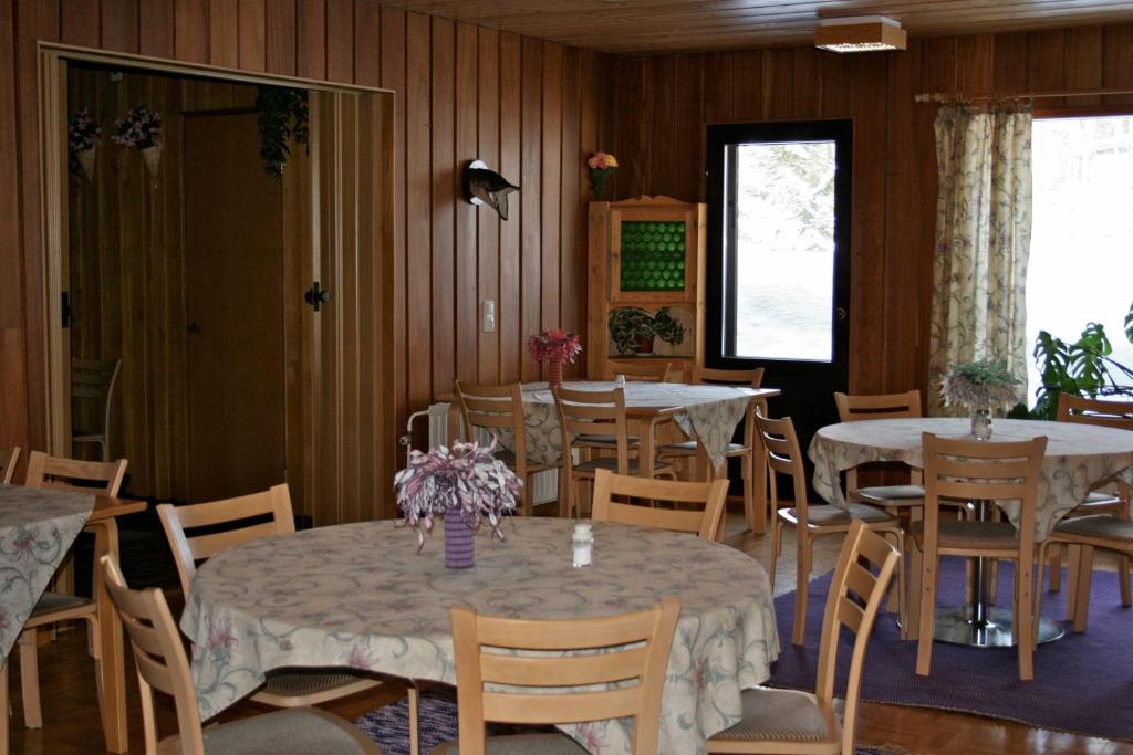 a dining room with two tables and chairs with flowers on them at Gasthaus Punkaharju in Punkaharju