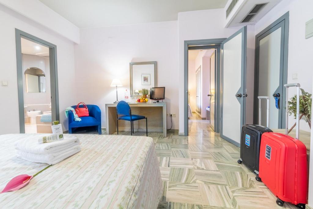 ロハにあるHotel Abades Manzanilのベッドと赤いスーツケースが備わるホテルルームです。