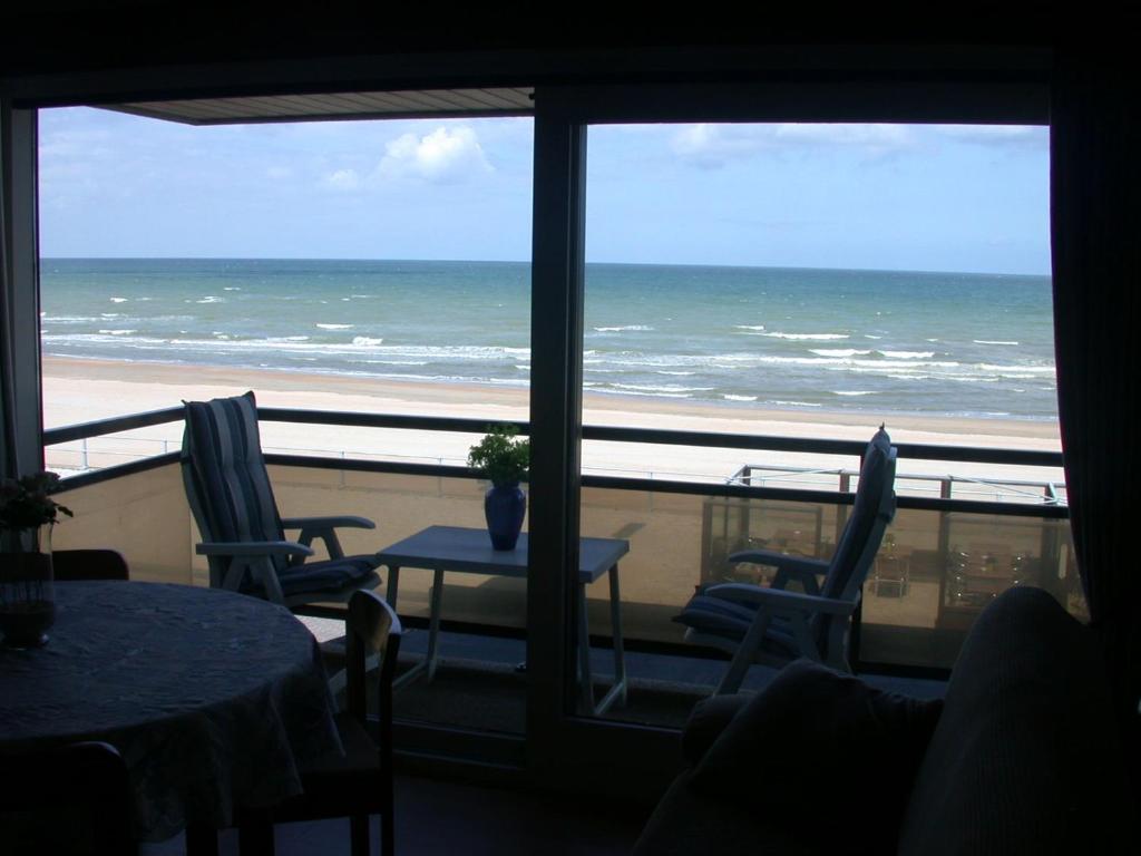 a room with a view of the ocean from a balcony at Studio Zeezicht De Sloep Koksijde in Koksijde