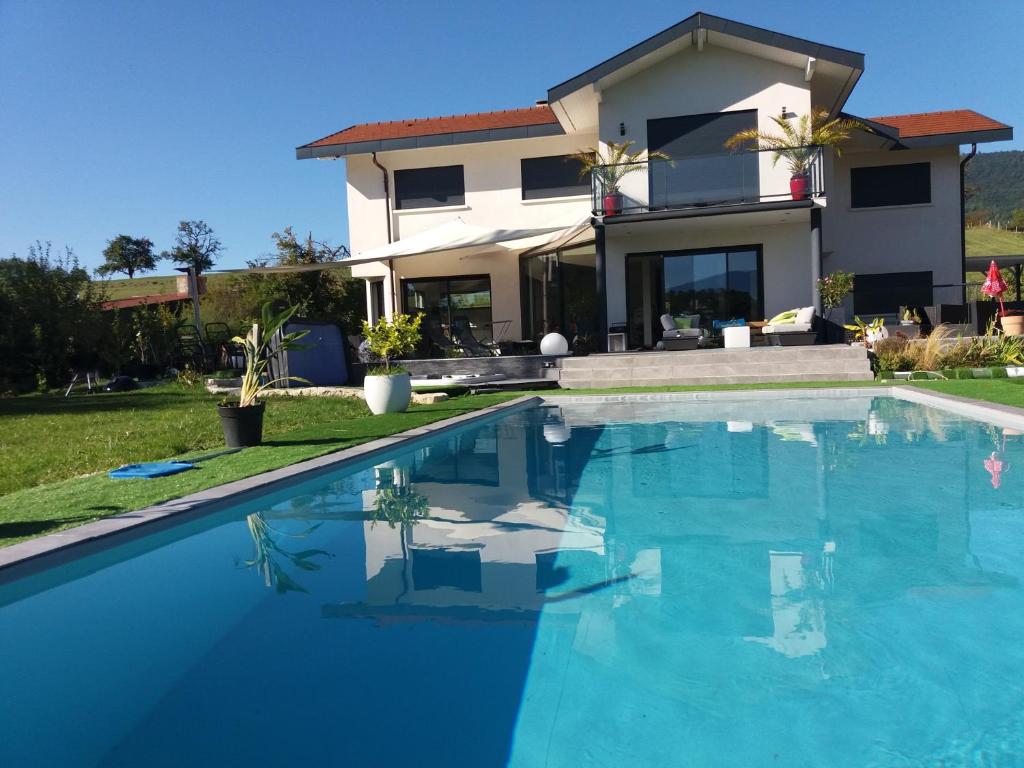 a villa with a swimming pool in front of a house at Chambres, cuisine, piscine, spa, billards, airhockey, nature in Fillinges