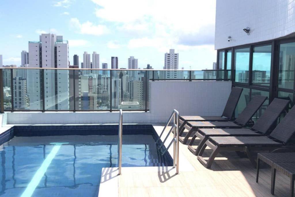 un balcon avec une piscine sur le toit d'un immeuble dans l'établissement Conforto e praticidade em Boa Viagem., à Récife