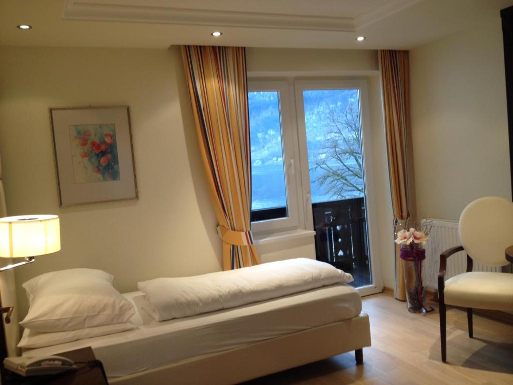 a bedroom with a bed and a large window at Hotel & Gasthof Fürberg in Sankt Gilgen