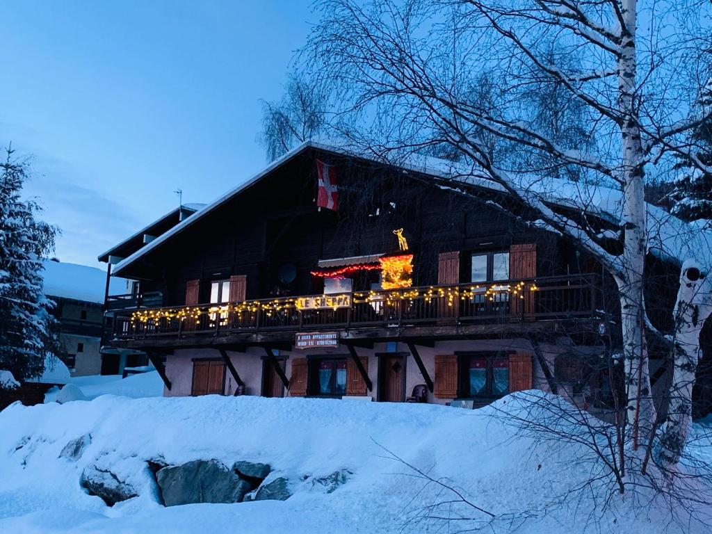 a house with a deck with christmas lights on it at APPARTEMENT PLEIN SUD AUX SAISIES N°6 in Les Saisies