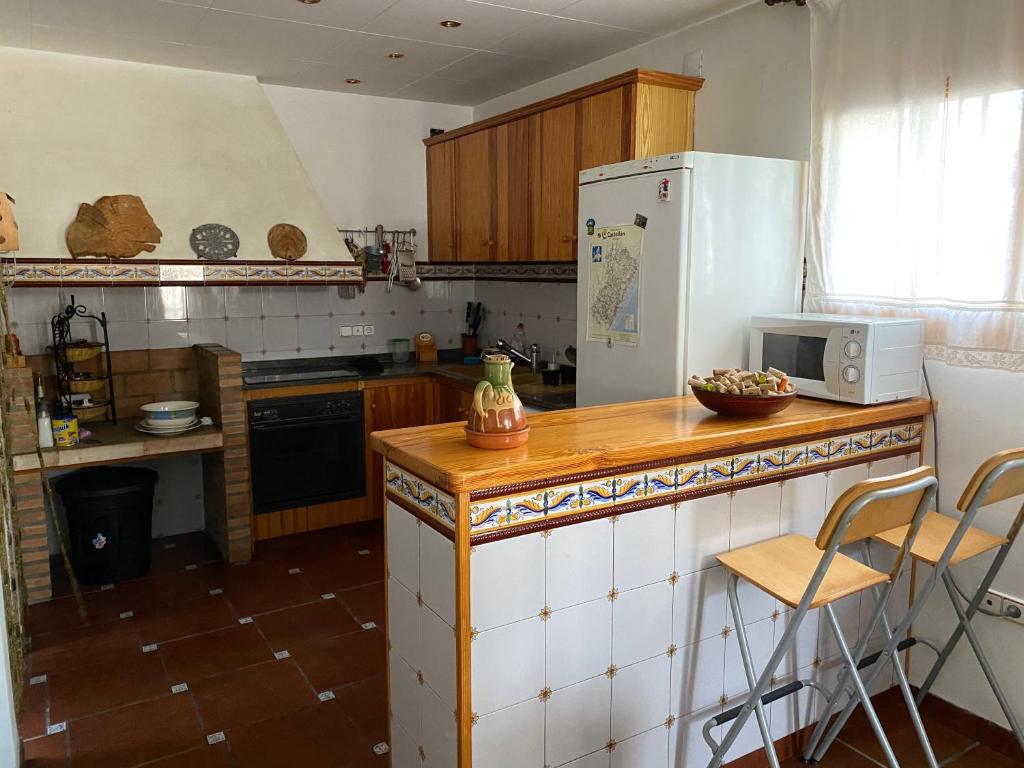 een keuken met een koelkast en een aanrecht met stoelen bij Ca Ramonet in Arañuel