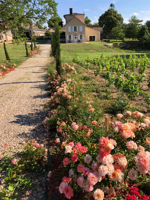 a garden of flowers with a house in the background at Allée des Roses in Saint-Philippe-dʼAiguille