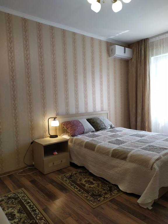een slaapkamer met een bed en een tafel met een lamp bij Элегантная двухкомнатная квартира в центре in Novorossiejsk