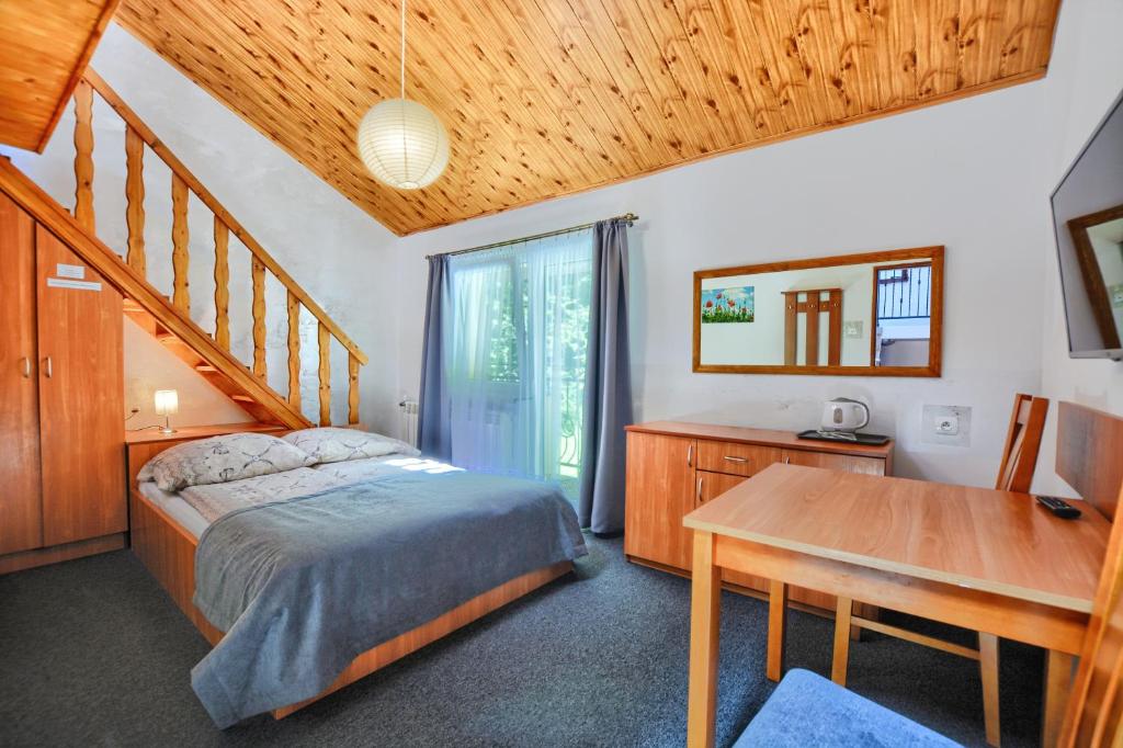 1 dormitorio con cama, escritorio y mesa en Willa Mak en Krynica Zdrój