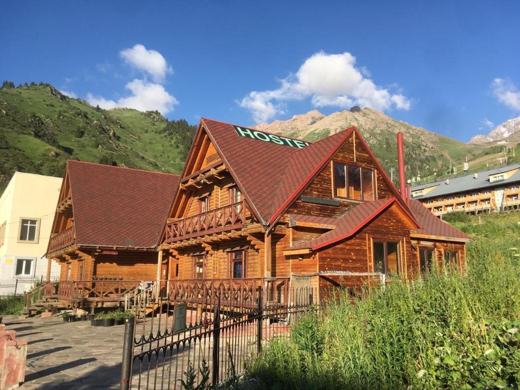 a large wooden house with a brown roof at Hostel SHYMBULAK in Almaty