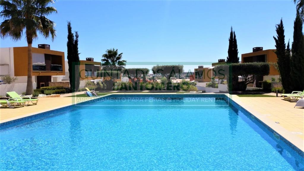 uma piscina num resort com palmeiras e edifícios em Apartamento Vitismar CA em Guia