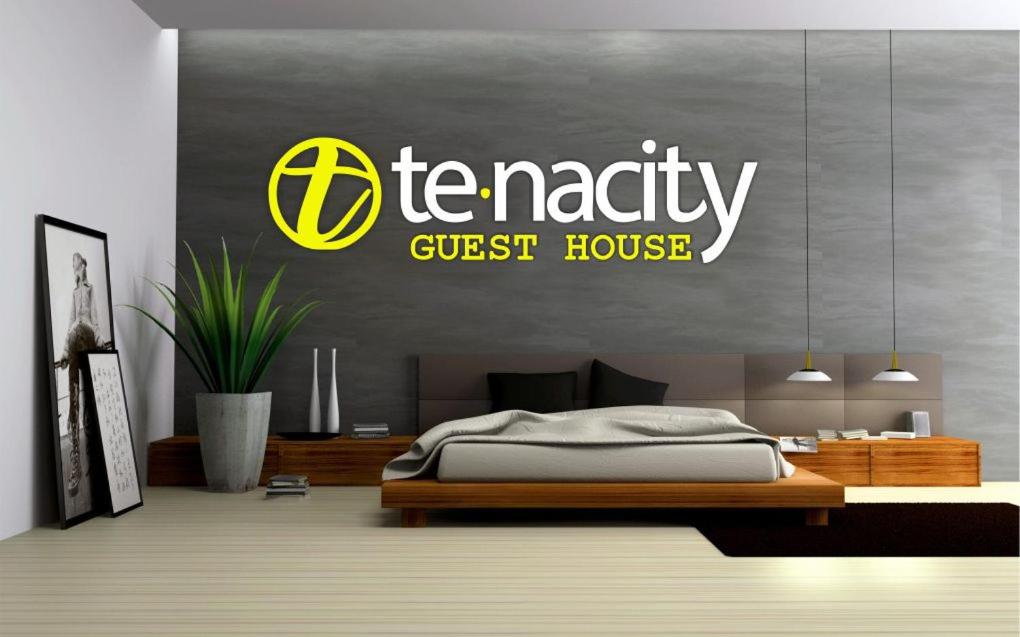 Tenacity Guesthouse - Riviera Park في مافكينج: غرفة نوم مع علامة بيت ضيافة على الحائط