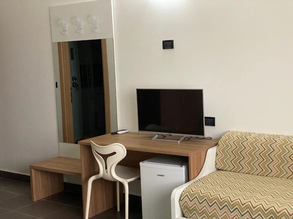 een kamer met een bureau, een televisie en een stoel bij Pansini Hotel Residence in Badolato