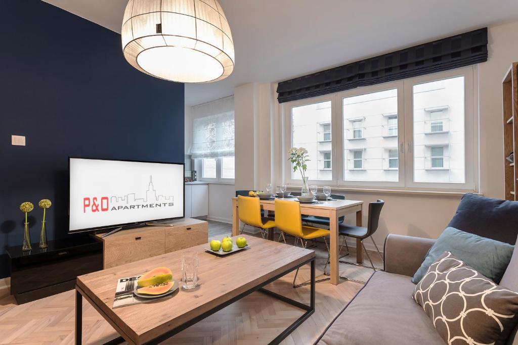 a living room with a couch and a table with a tv at Nowogrodzka 38 Serviced Apartments in Warsaw