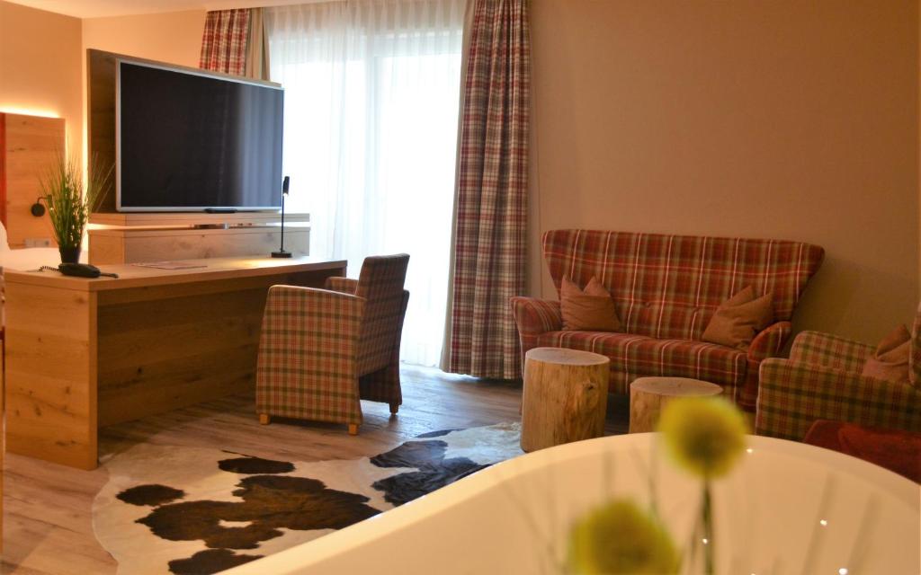 a living room with a flat screen tv and a couch at Hotel Bergwirt in Herrieden