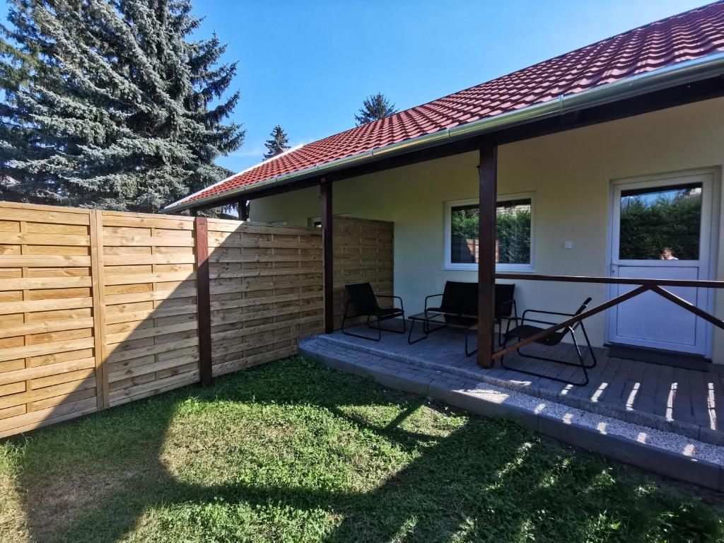 een huis met een hek en twee stoelen op een terras bij Vali néni kifőzde és apartman in Kismaros