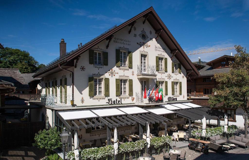 a white building with awnings in front of it at Hotel Olden in Gstaad