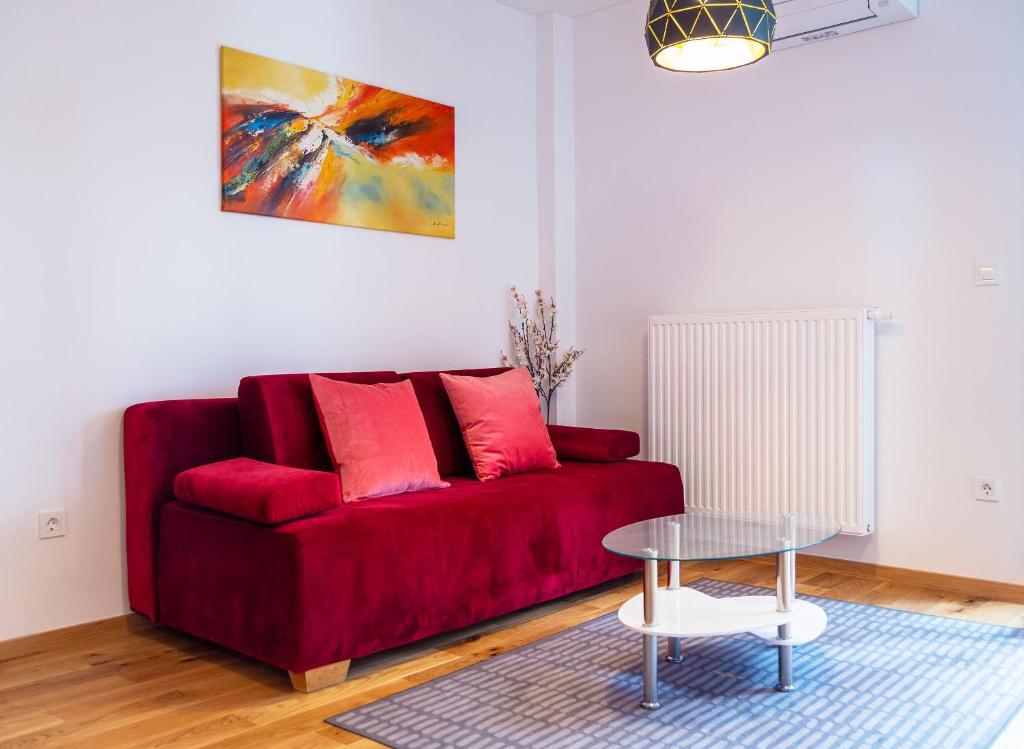Histrias Apartments Koper في كوبر: أريكة حمراء في غرفة معيشة مع طاولة