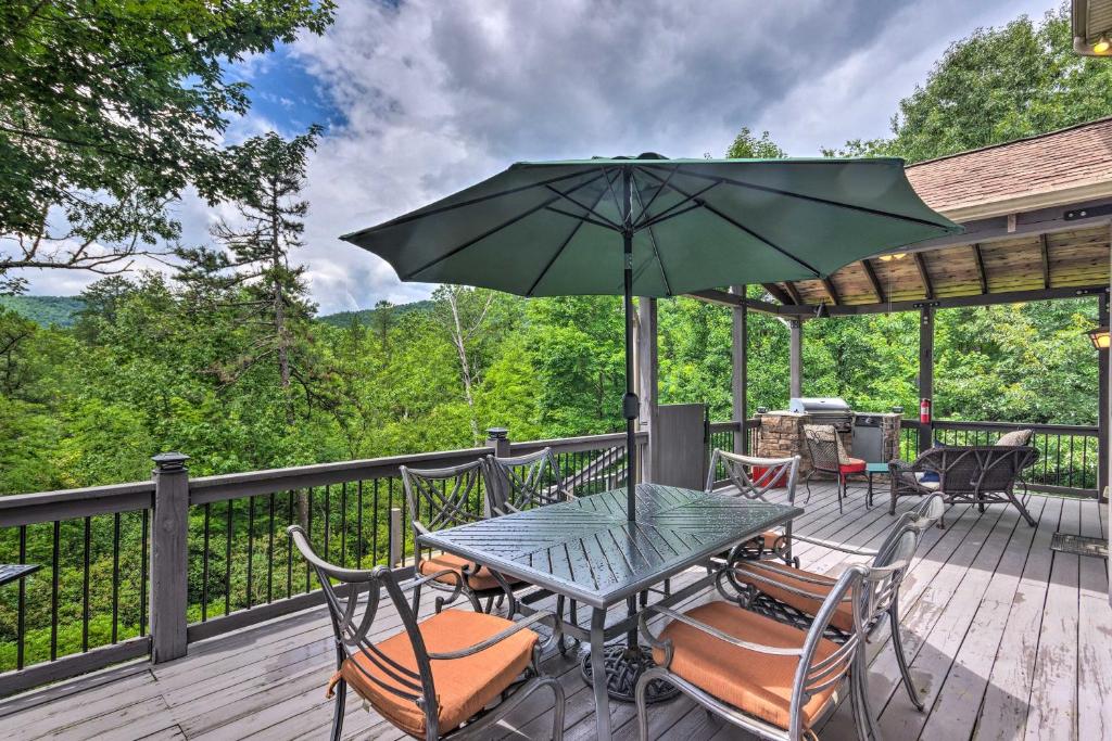 einem Tisch mit Stühlen und einem Sonnenschirm auf einer Terrasse in der Unterkunft Peaceful Pisgah Mountain Getaway with Hot Tub! in Pisgah Forest