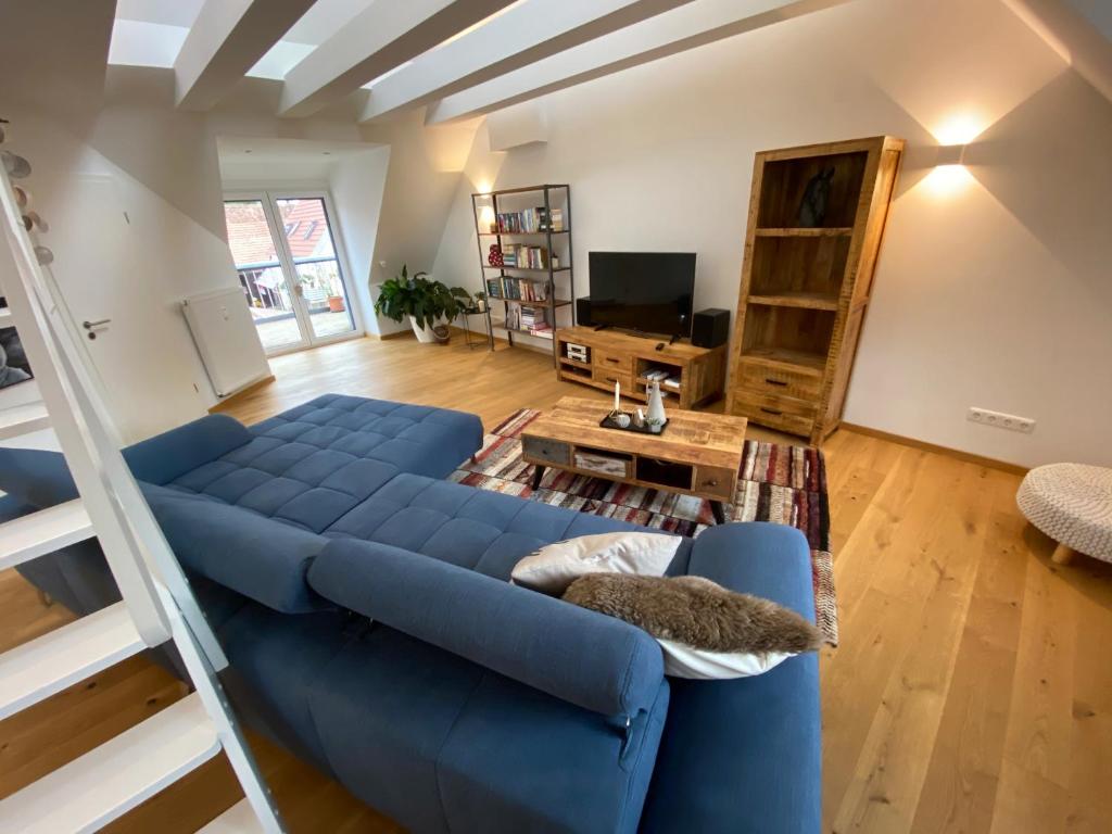 a living room with a blue couch and a table at modernes Penthouse, nahe Würzburg in Würzburg