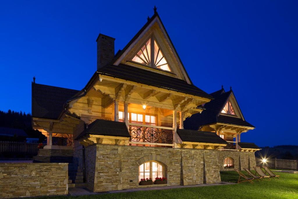 a large house with a gambrel roof at night at Góralska Zagroda in Dzianisz