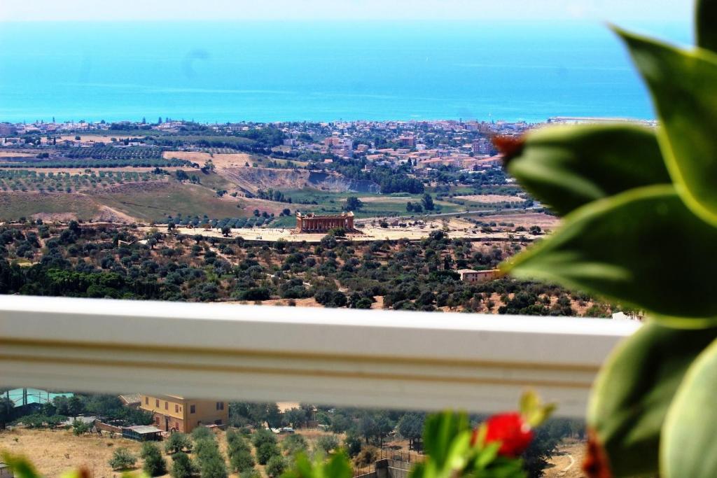 einen Blick auf eine Stadt aus einem Fenster mit einer Pflanze in der Unterkunft Attico d'arte sulla Valle dei Templi in Agrigento