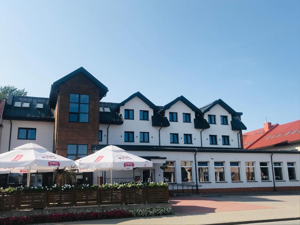 a large white building with umbrellas in front of it at Pokoje Hotelowe LUPUS in Gołdap