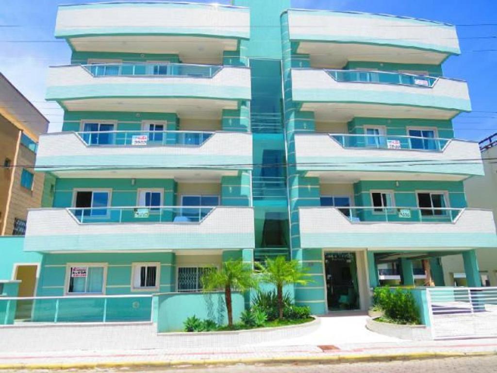 un edificio azul y blanco con una palmera delante en Res Costa Verde, en Bombinhas