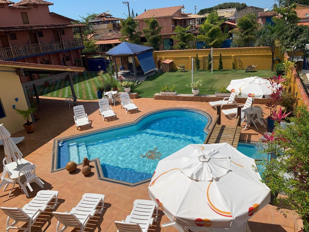 - une piscine avec des chaises et des parasols à côté dans l'établissement Pousada dos Corais, à Itaúnas