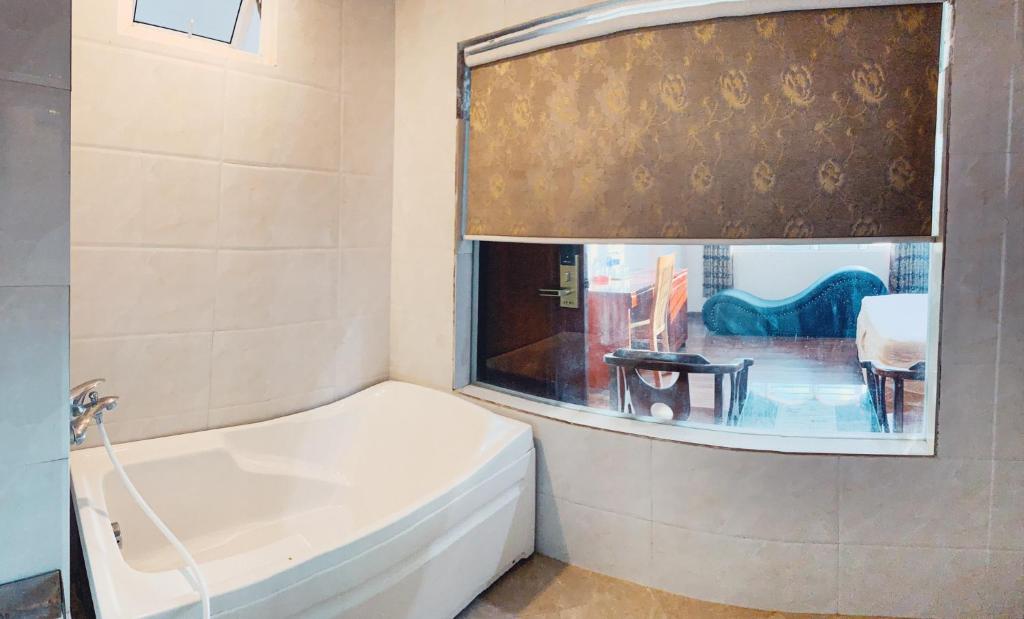 a white bath tub in a bathroom with a window at Hoang Ngan 1 Hotel - TP. Vinh in Vinh