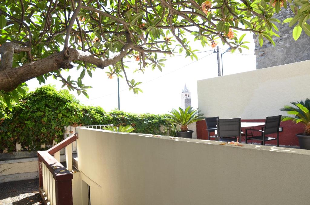 a balcony with a table and chairs and a tree at O Clube in Porto da Cruz