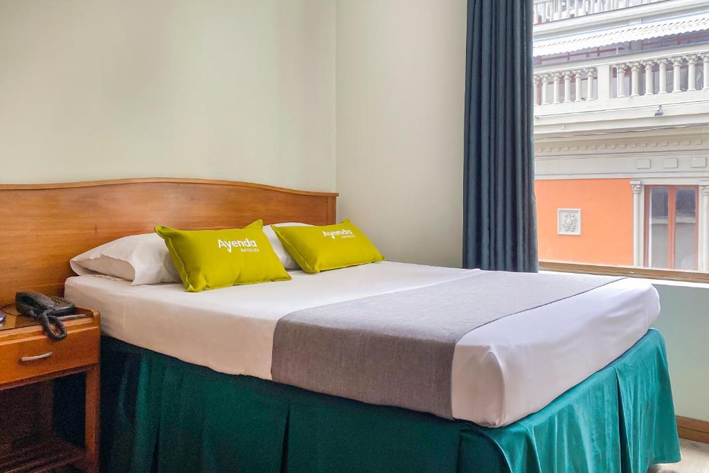 Un dormitorio con una cama con almohadas amarillas y una ventana en Ayenda 1140 Roma Plaza, en Manizales