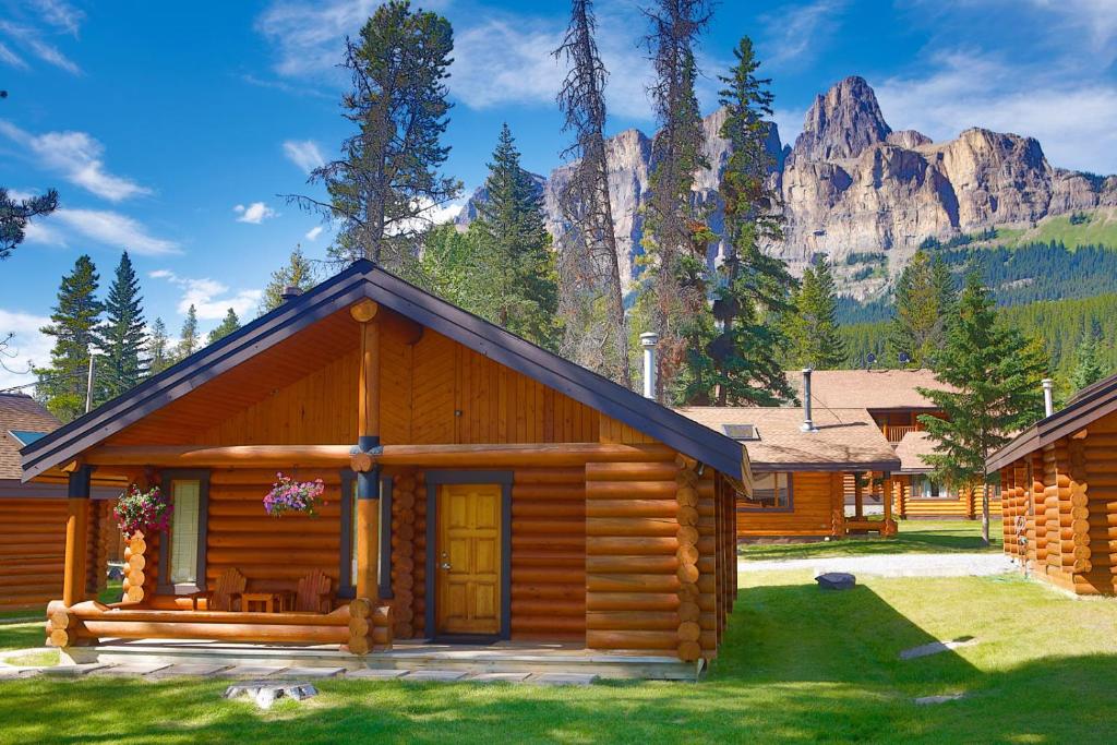 a large wooden cabin with a view of a mountain range at Castle Mountain Chalets in Castle Junction
