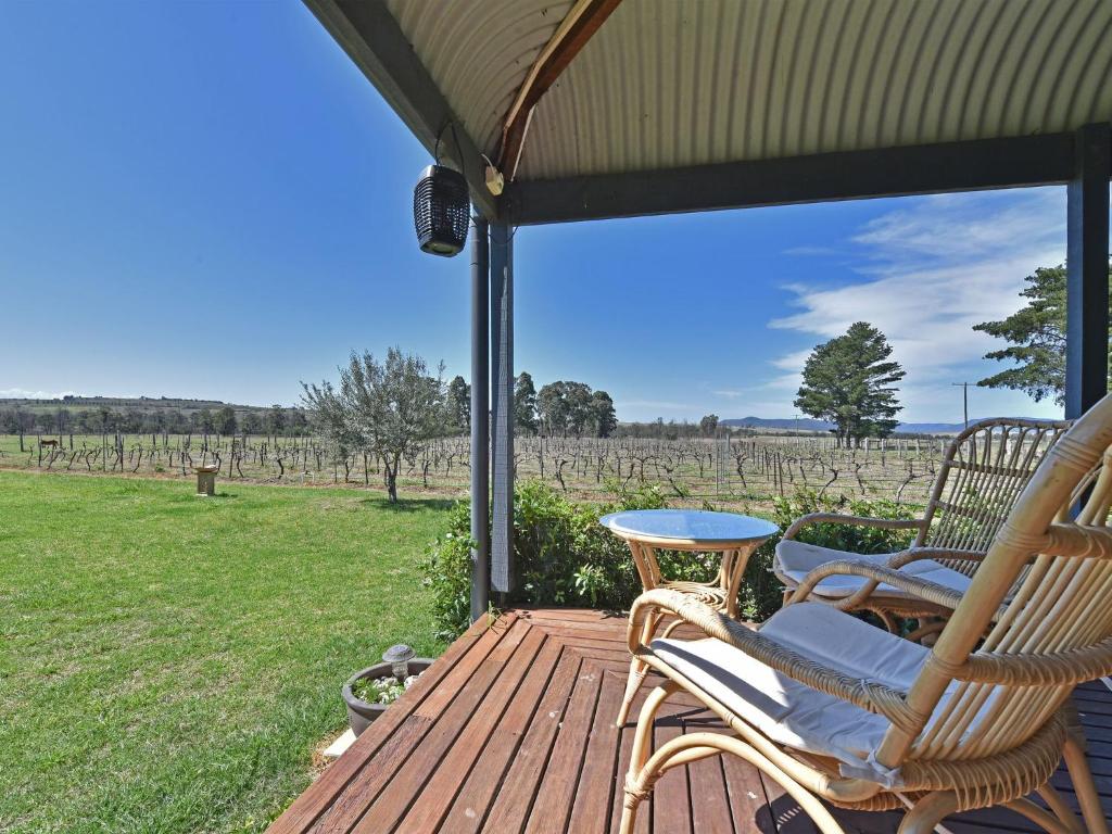 eine Terrasse mit Stühlen und einem Tisch und Blick auf ein Feld in der Unterkunft Soldiers Cottage picturebook vineyard home in Bulga