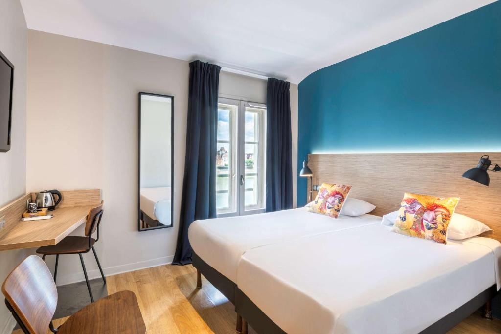 マコンにあるHôtel du Nord, Sure Hotel Collection by Best Westernのベッド2台とデスクが備わるホテルルームです。