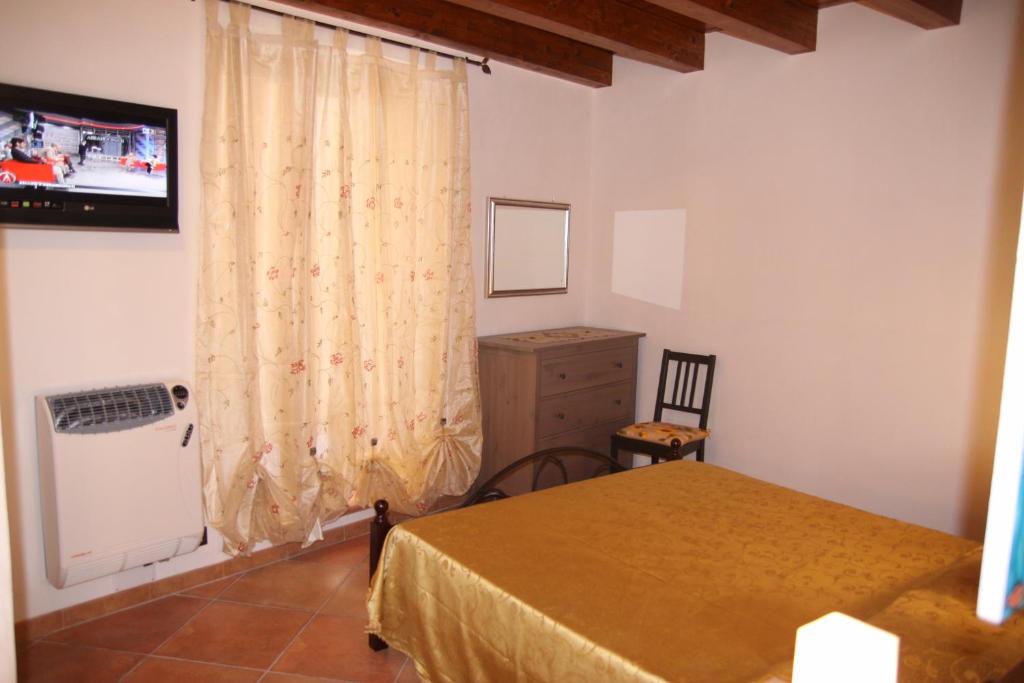 a bedroom with a bed and a dresser and a television at La Finestra Sotto La Rocca in Cefalù