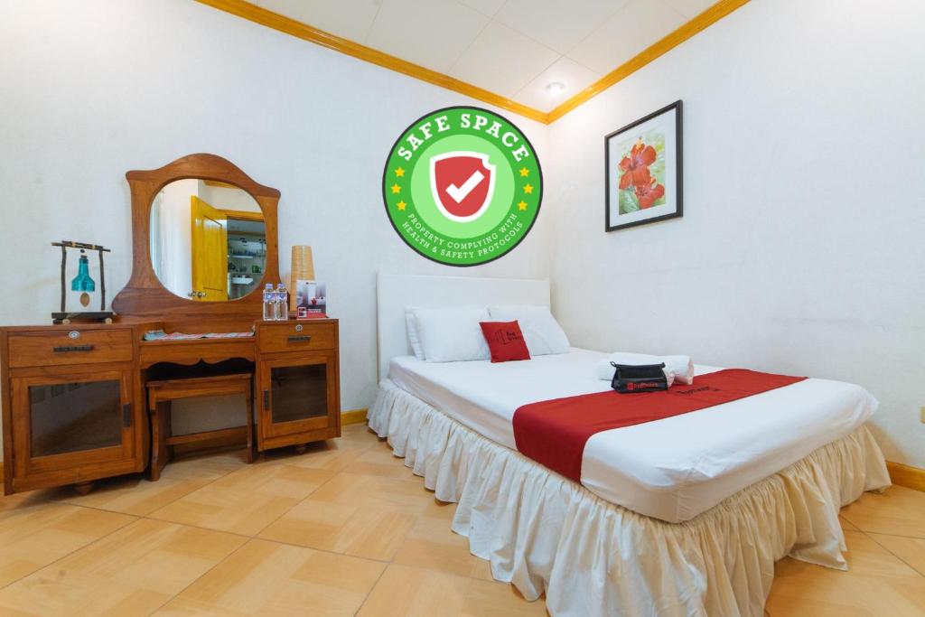 1 dormitorio con cama, escritorio y espejo en RedDoorz @ Arimbay Legazpi City, en Legazpi
