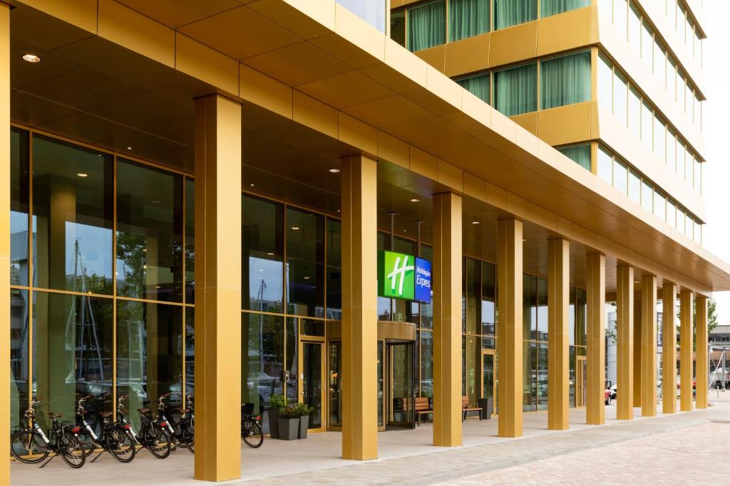 a building with a bunch of bikes parked outside of it at Holiday Inn Express Amsterdam - North Riverside by IHG in Amsterdam
