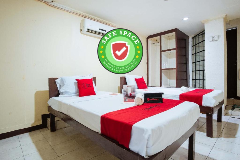 two beds in a room with a green sign on the wall at RedDoorz @Downtown Bacolod in Bacolod