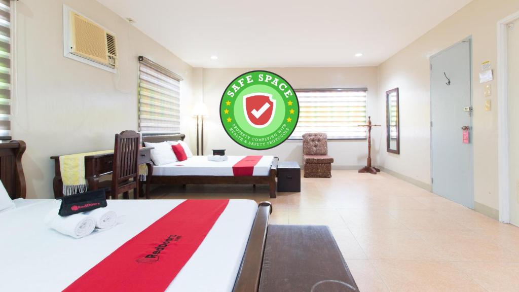 a room with two beds and a green sign on the wall at RedDoorz at Teofila Lodge in Vigan