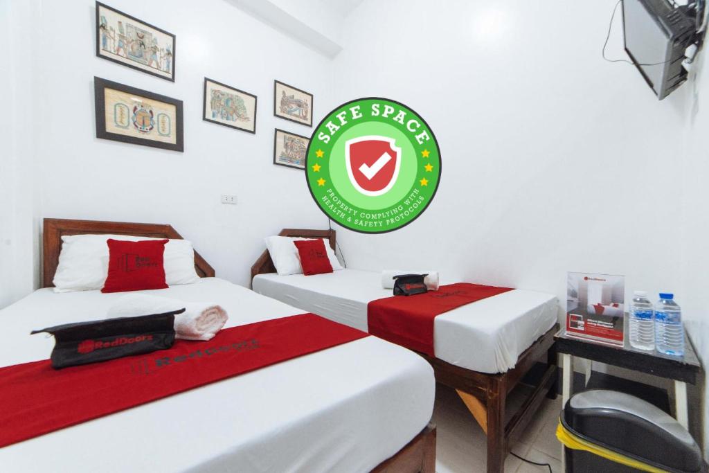 a room with two beds and a green sign on the wall at RedDoorz @ Plaza Jaro Iloilo in Iloilo City