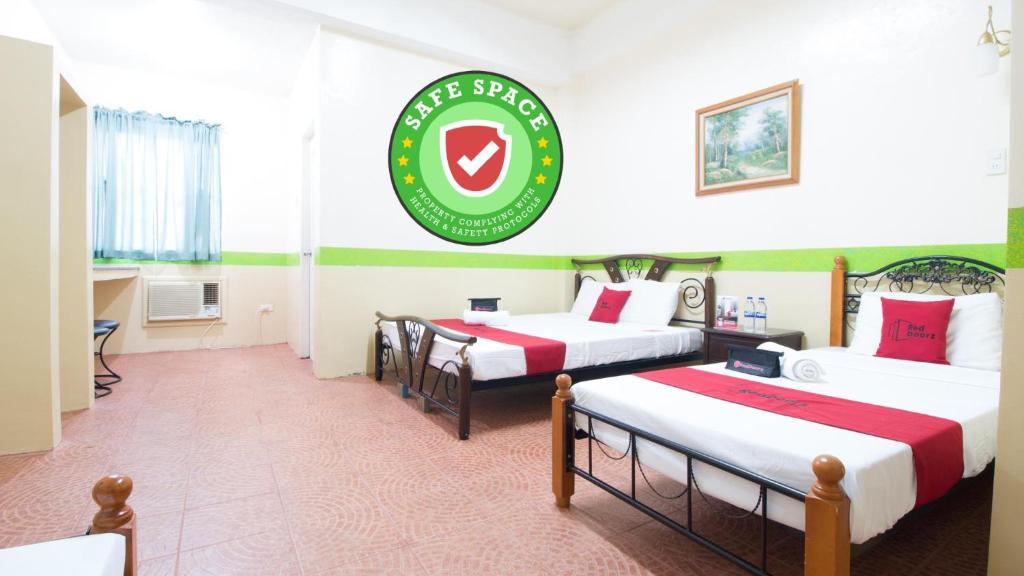um quarto de hotel com três camas e uma placa na parede em RedDoorz Praferosa Resort Hotel Calamba em Calamba