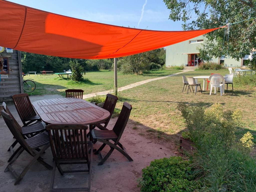 a table and chairs under an orange umbrella at Auberge de Jeunesse HI Belle-Île-en-Mer in Le Palais